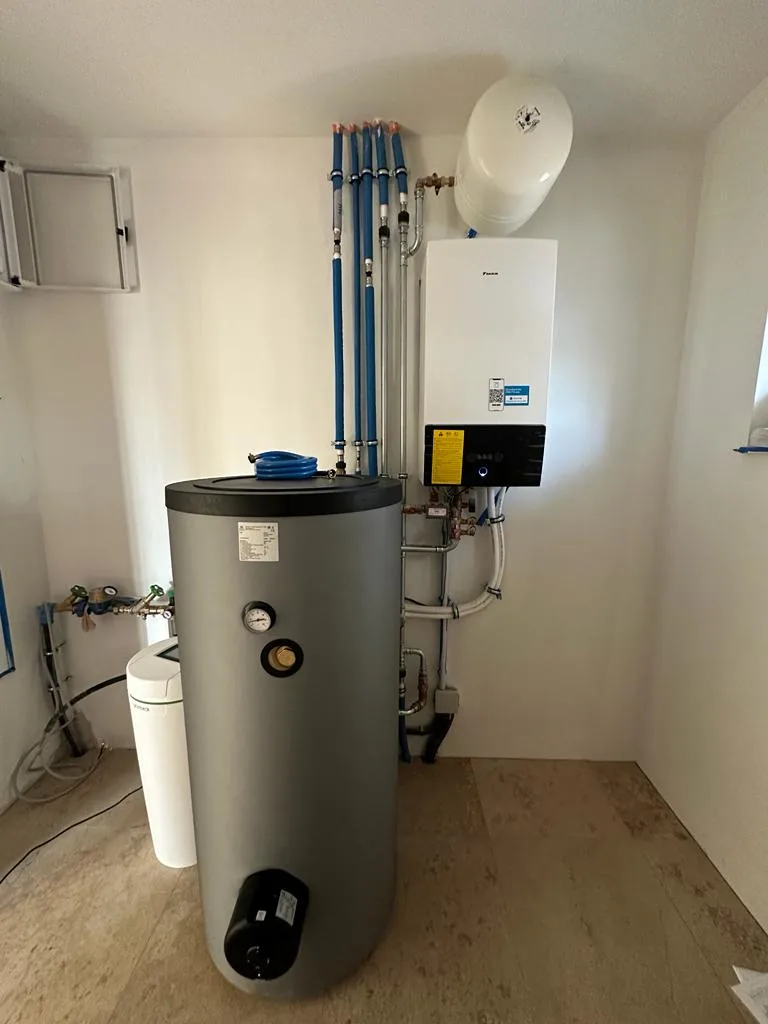 Technikraum mit grauem Speicher, Innengerät an der Wand und blau gedämmten Leitungen