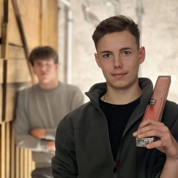 Zwei Lehrlinge auf der Baustelle, einer hält eine Wasserwaage