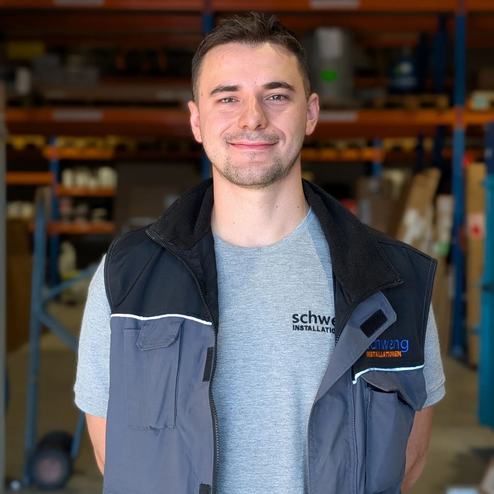 Servicetechniker Nermin in Arbeitsweste mit Schweng-Logo im Lager