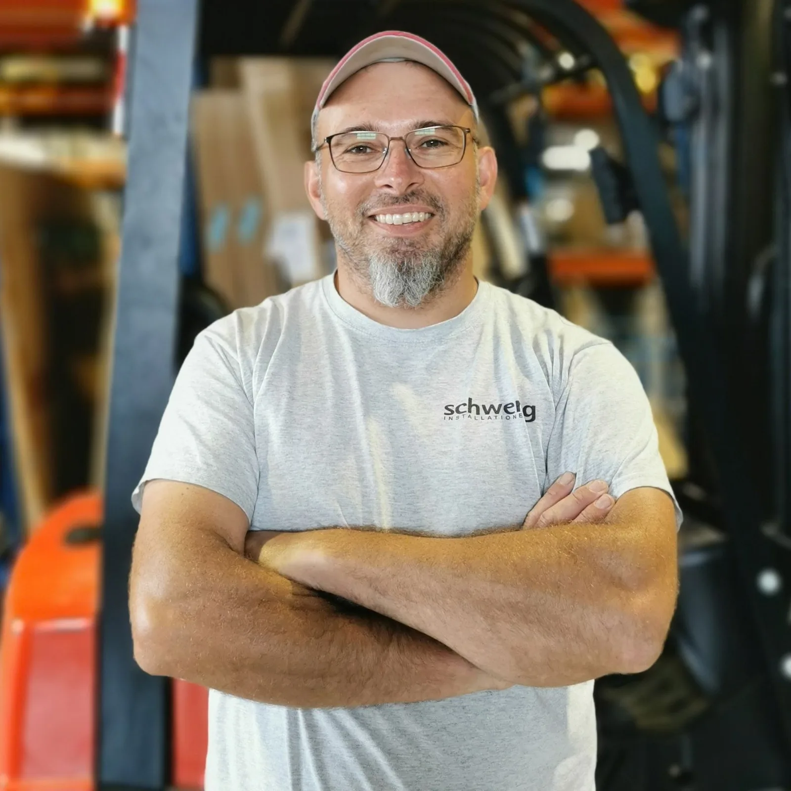Servicetechniker Rudolf mit Kappe und Schweng-Shirt, Arme verschränkt