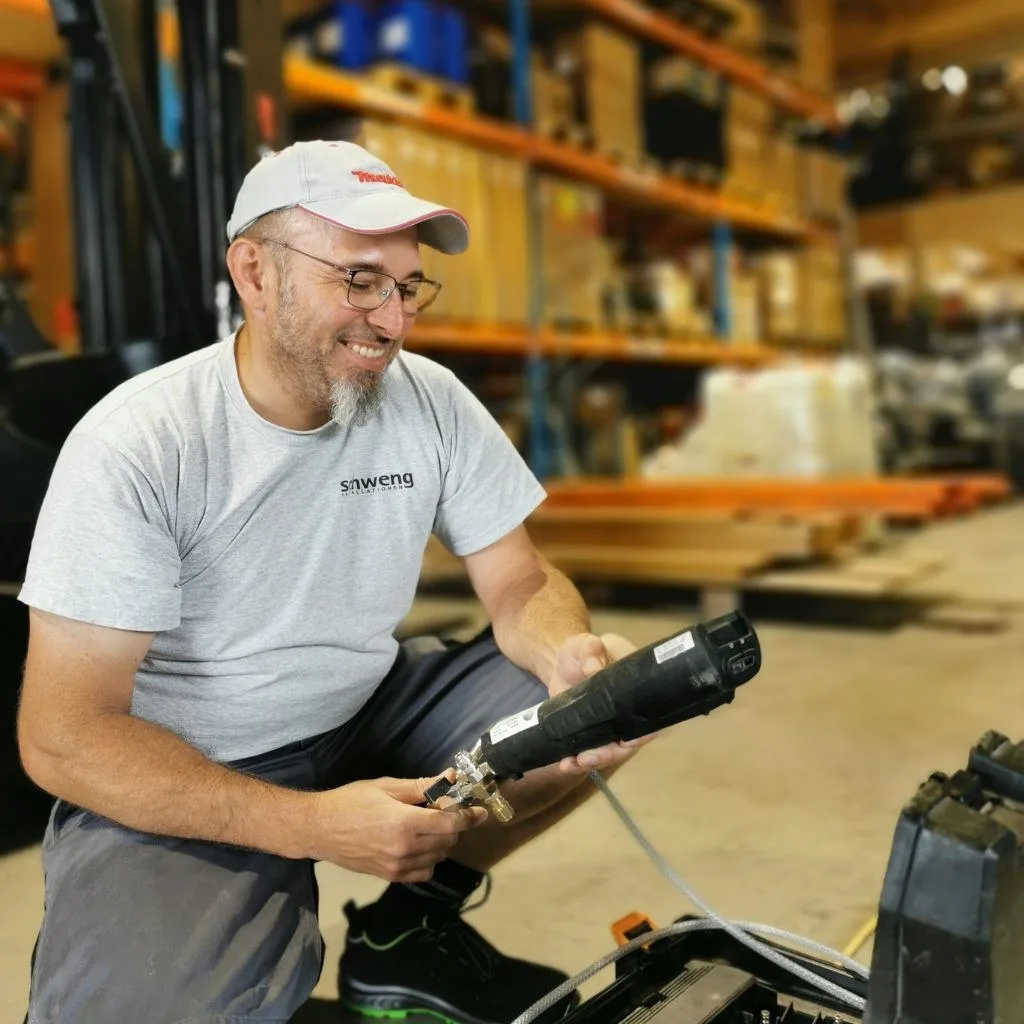 Servicetechniker im Schweng-Shirt mit einem Messgerät im Lager